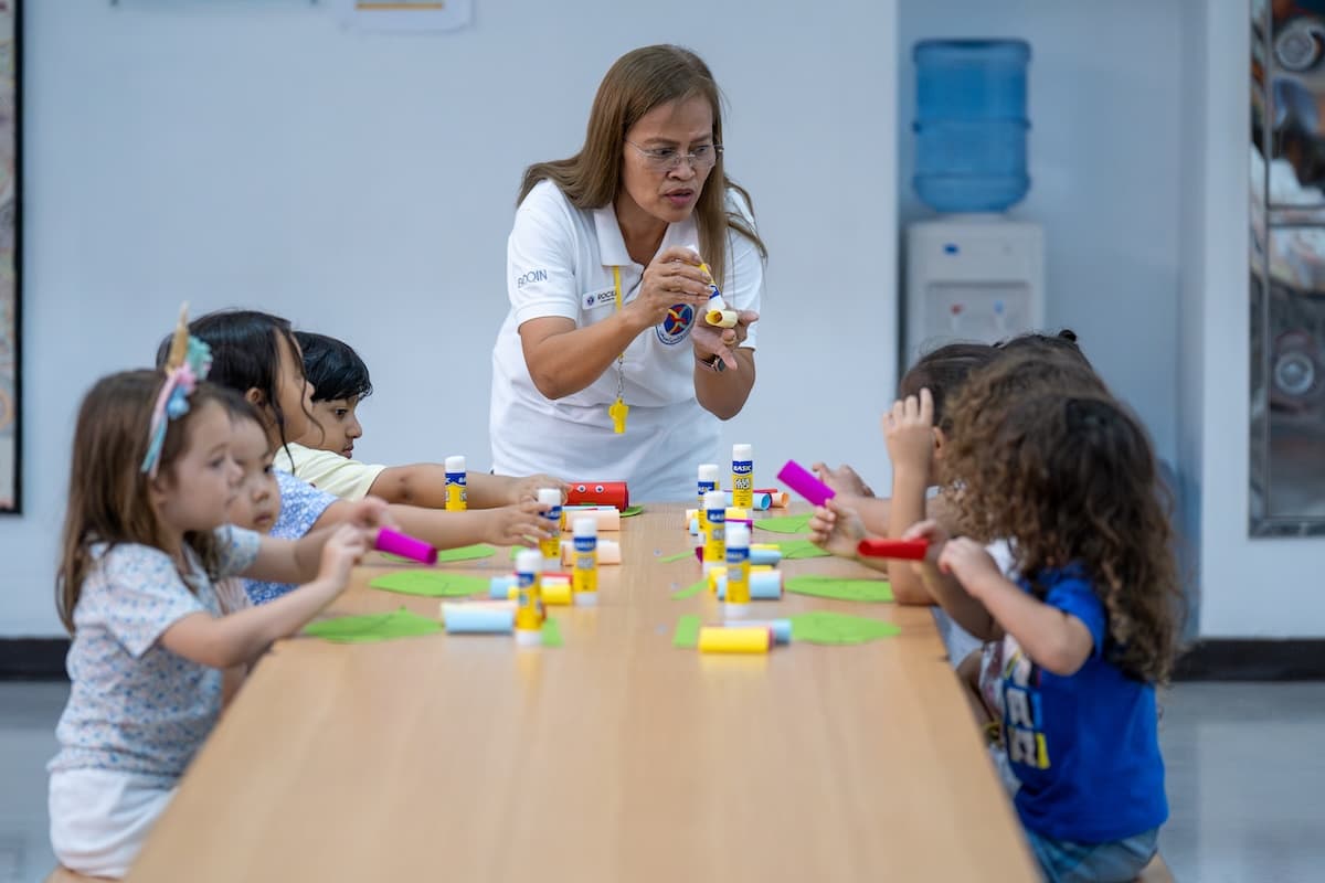 Teacher guides children during a craft activity